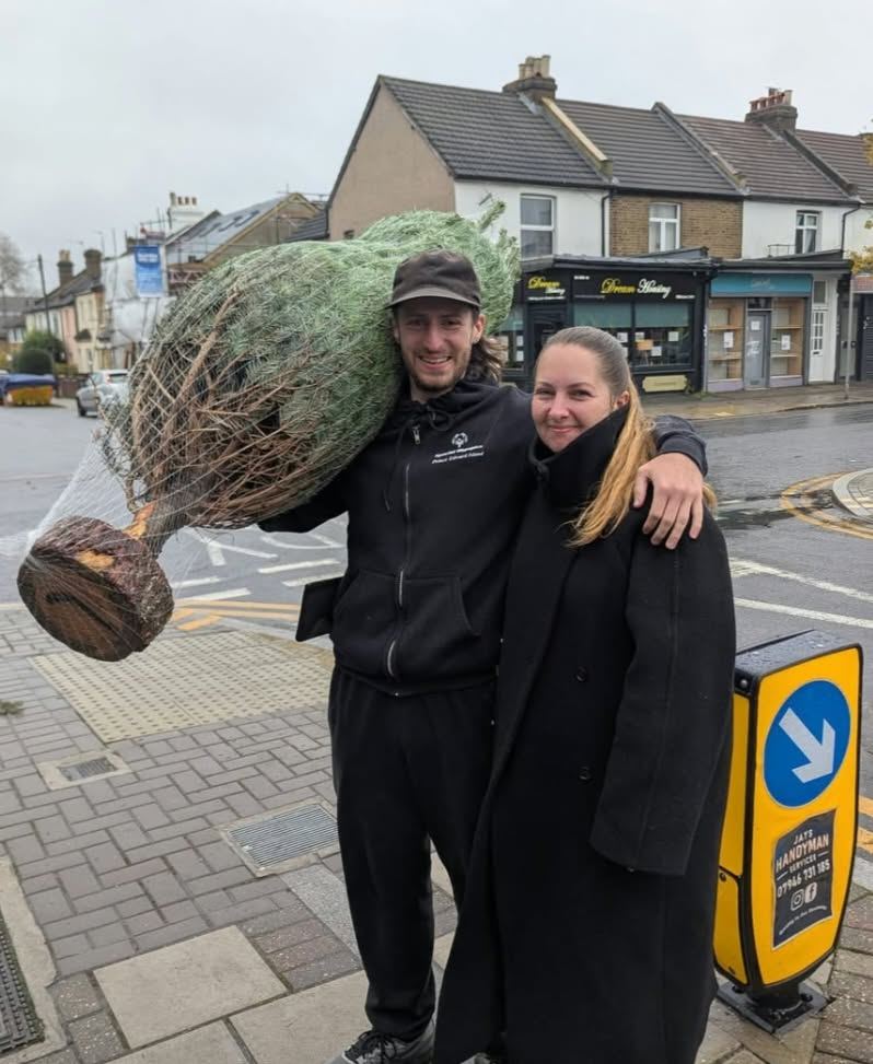 A couple with their netted Christmas tree carried over his shoulder
