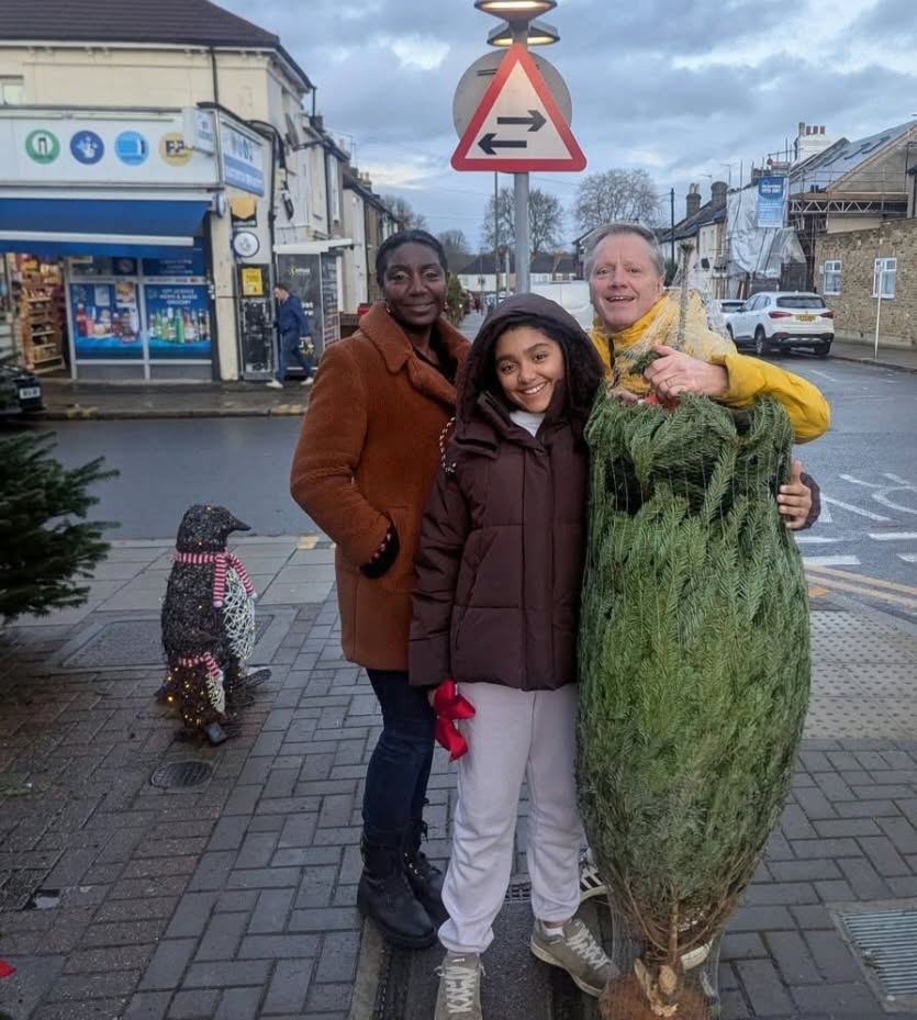 A family with their netted tree next to a light-up penguin decoration