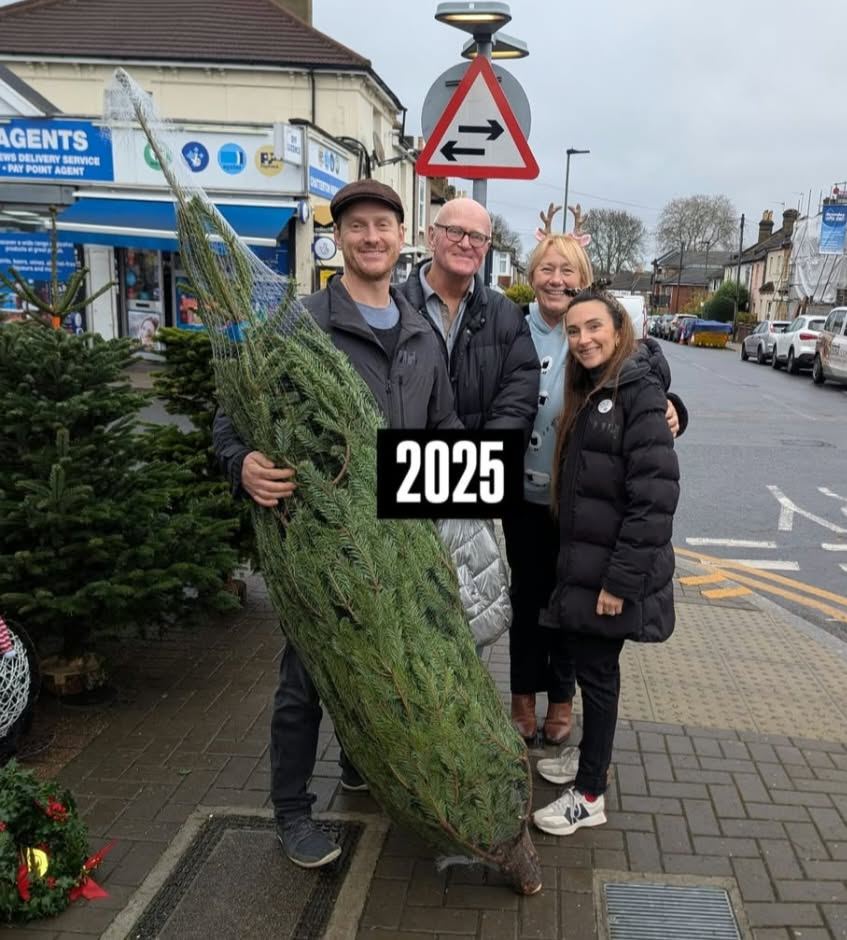 Friends and family with their netted tree, one wearing reindeer antlers