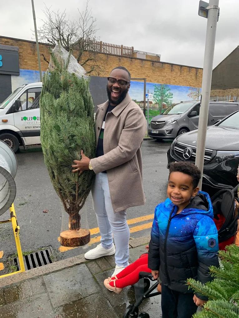A dad and his son with their netted tree by the loading bay and the Co-op mural